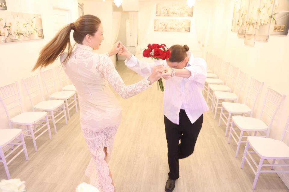 Two people dancing at a wedding, one in a white shirt and black pants, the other in a lace dress.