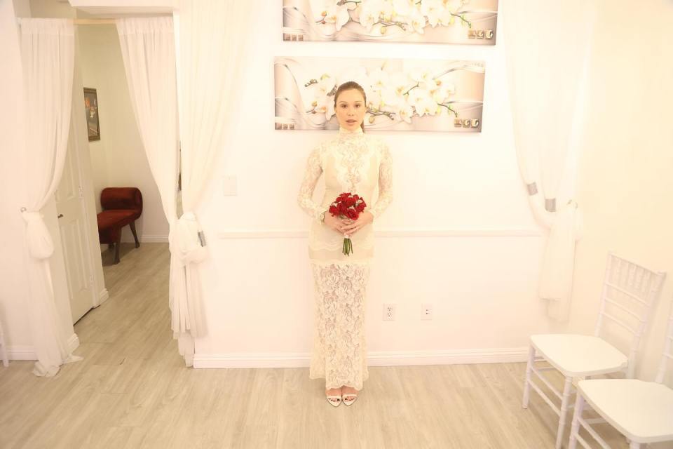 Woman in a lace wedding dress holding a bouquet of red roses.