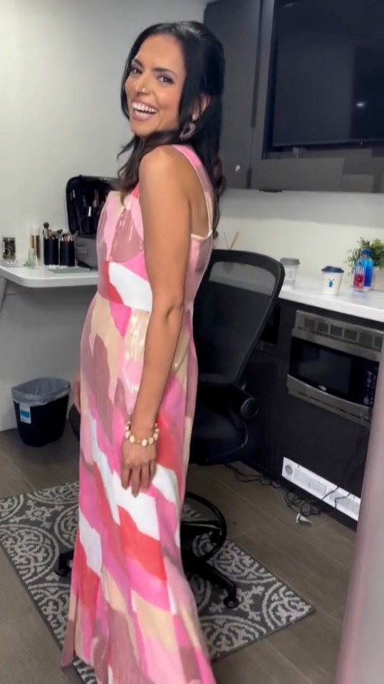 Woman in pink and peach patterned dress smiling.