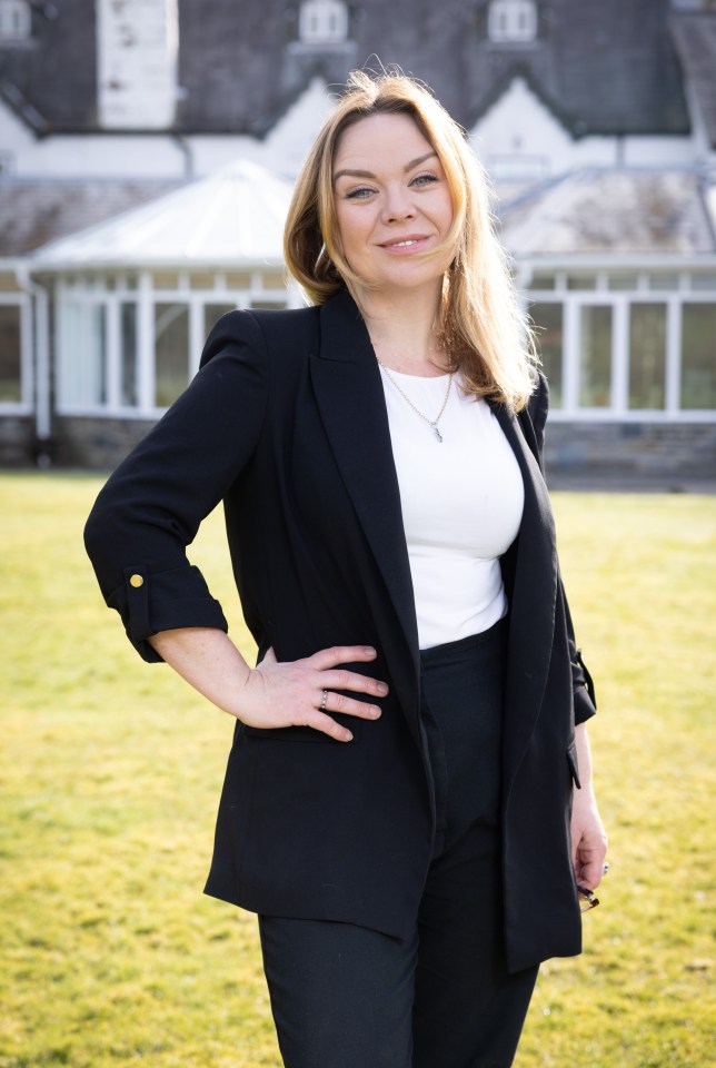 Portrait of a woman in a black blazer and pants, standing outside.