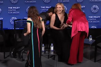 Kate Hudson having a wardrobe malfunction, helped by co-stars.