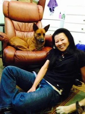 Woman sitting on the floor with her German Shepherd dog on a recliner.