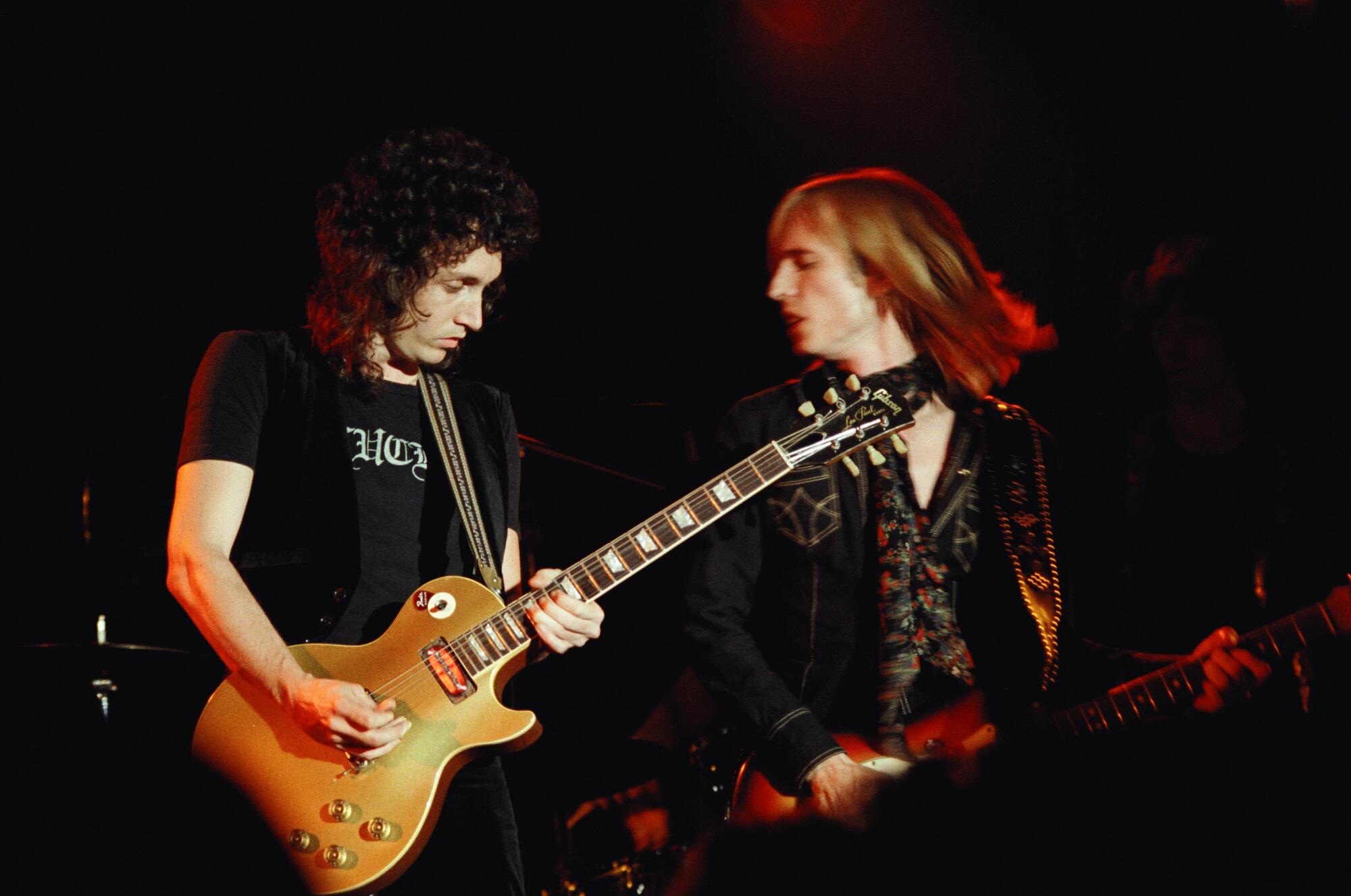 Mike Campbell and Tom Petty of Tom Petty and the Heartbreakers play guitar on stage.