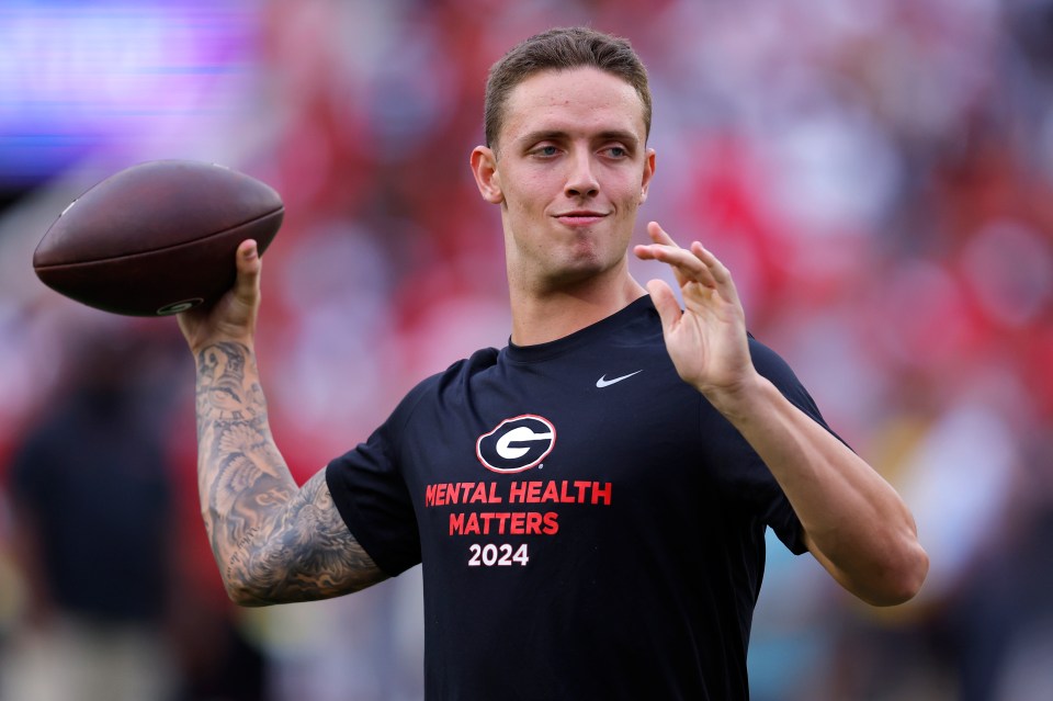 Carson Beck #15 of the Georgia Bulldogs warming up before a game.  His shirt says "Mental Health Matters 2024".