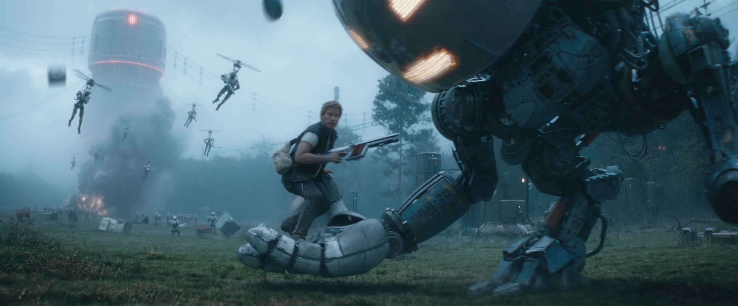 Keats (Chris Pratt) holds a laser blaster and gets picked up by his giant robot friend while helicopter droids fly his way in The Electric State