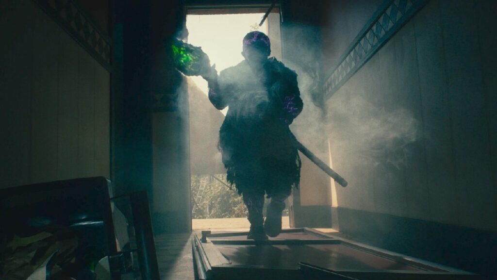 The titular hideously deformed hero (Peter Dinklage) breaks down a door in The Toxic Avenger remake.