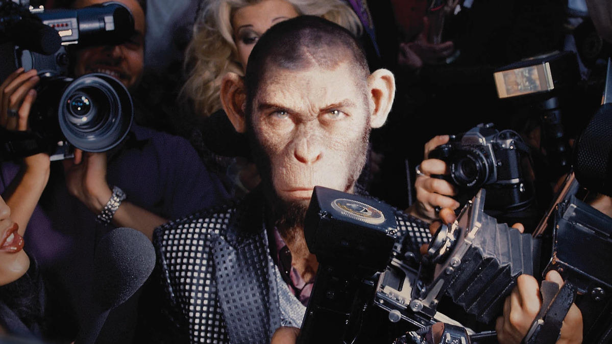 A monkey in a suit flanked by photographers in Better Man.