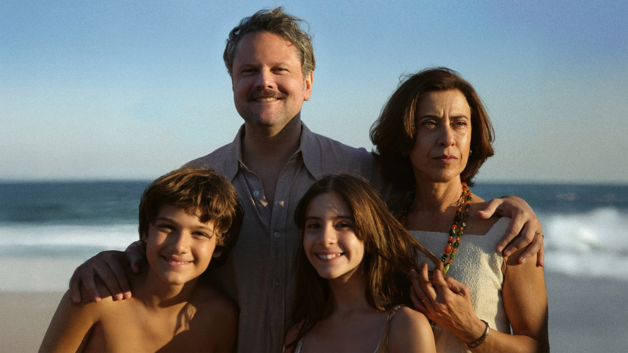 A family photo of a man, a woman, and their two children. The woman is staring off into the distance, while the other three family members smile at the camera.