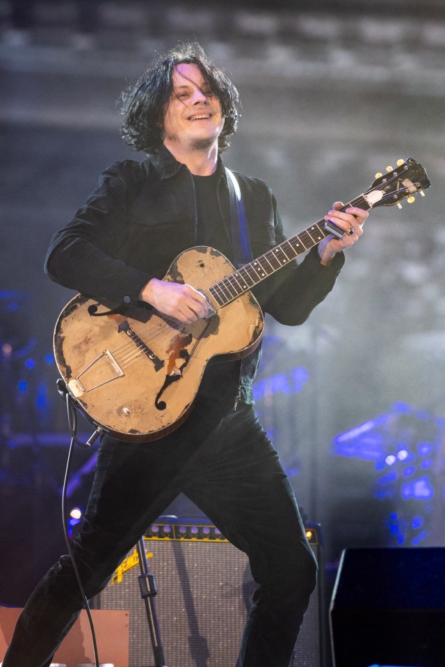 Jack White performing onstage with a guitar.