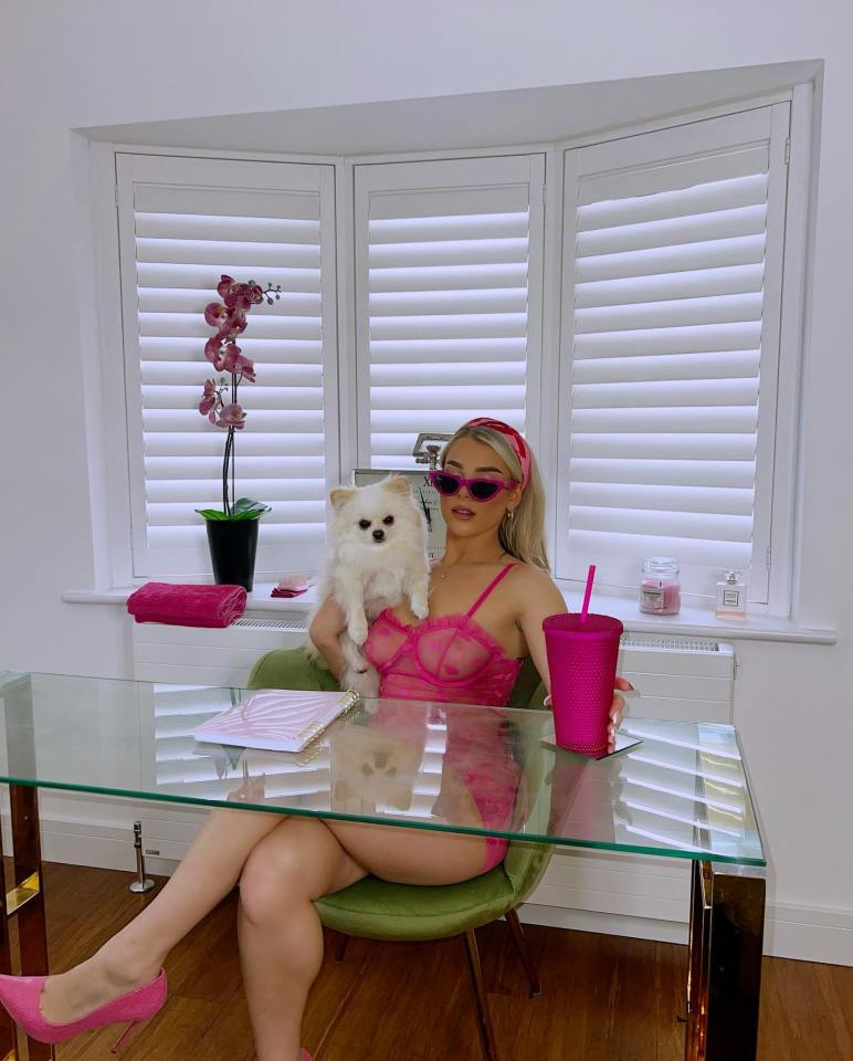 a woman sitting at a desk holding a small white dog