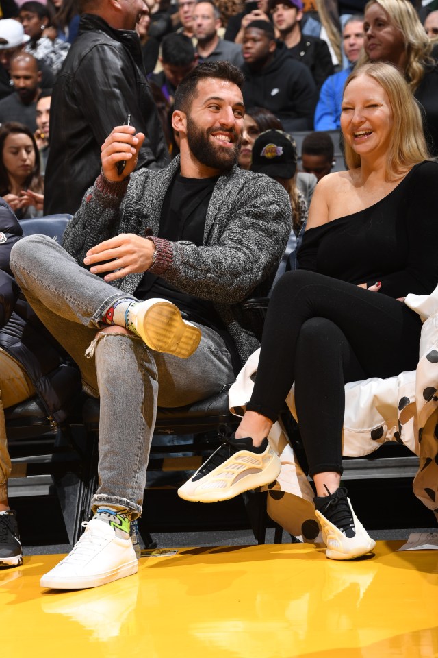 Sia and a man at an NBA basketball game.