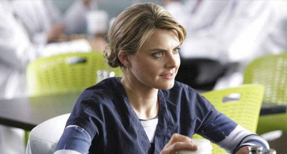 Woman in scrubs holding a coffee cup.