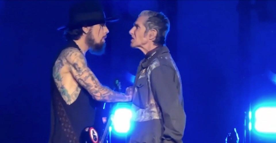 two men are standing next to each other on a stage and one of them has a tattoo on his arm