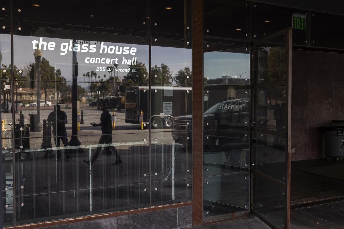 People are reflected in the glass front of Pomona concert venue the Glass House.