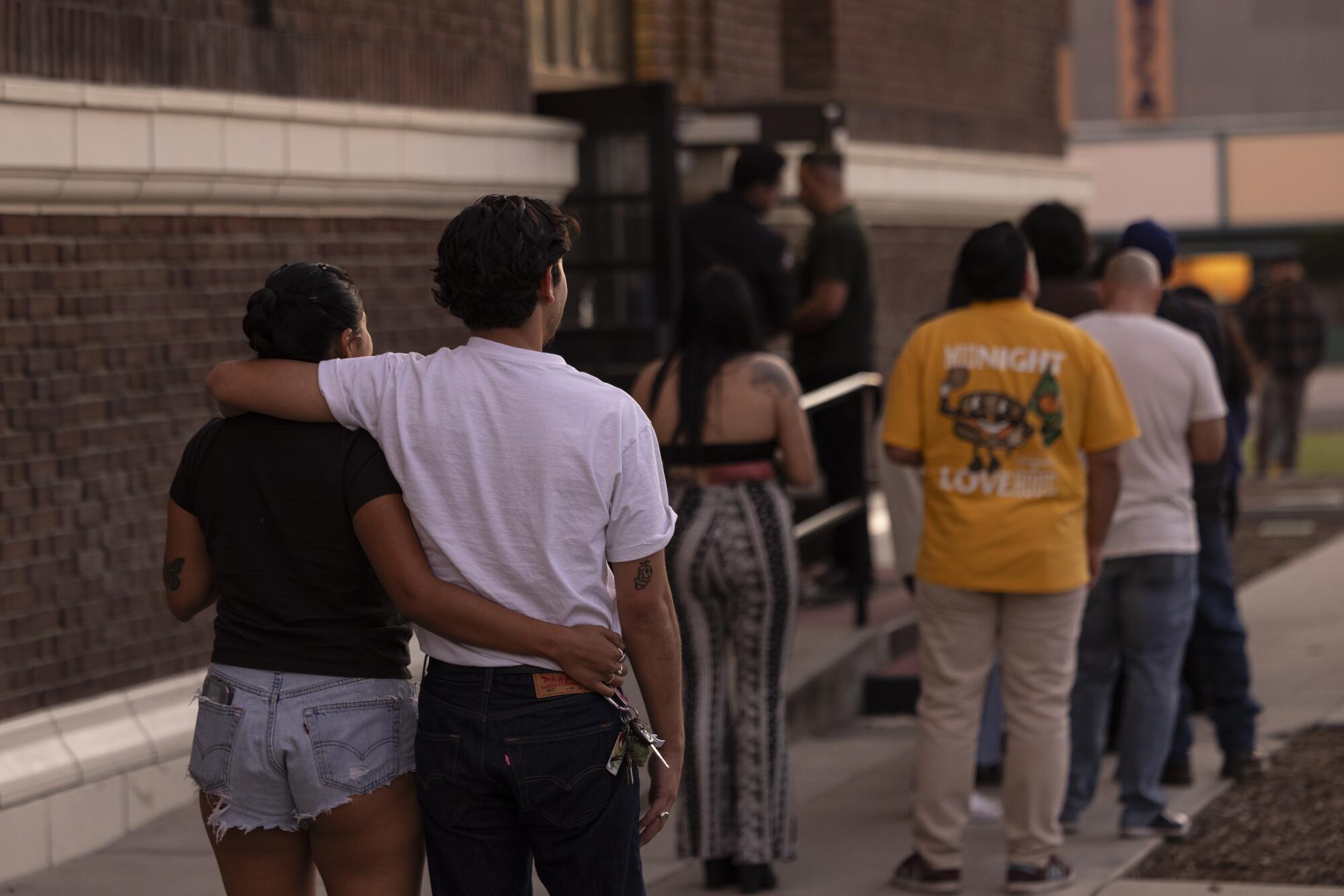 Concertgoers wait in line outside a building