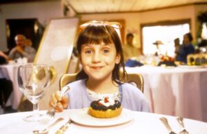 Mara Wilson as Matilda eating dessert in a restaurant.