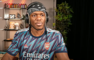 KSI wearing an Arsenal jersey and headphones.