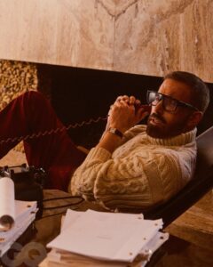 Ben Affleck on the phone, wearing glasses and a cable knit sweater.