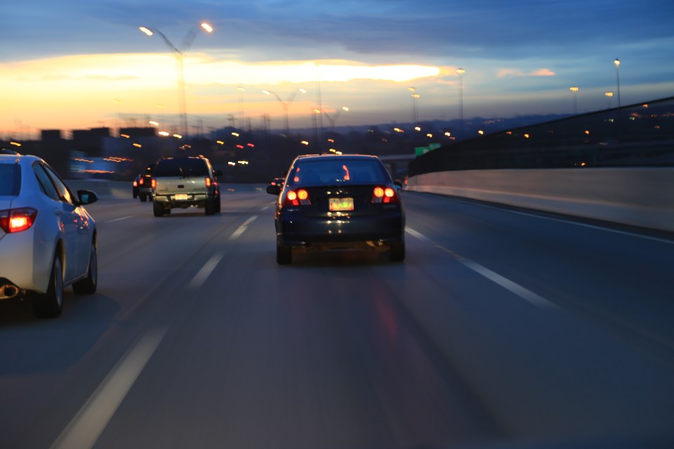 Cars driving on a highway at sunset.