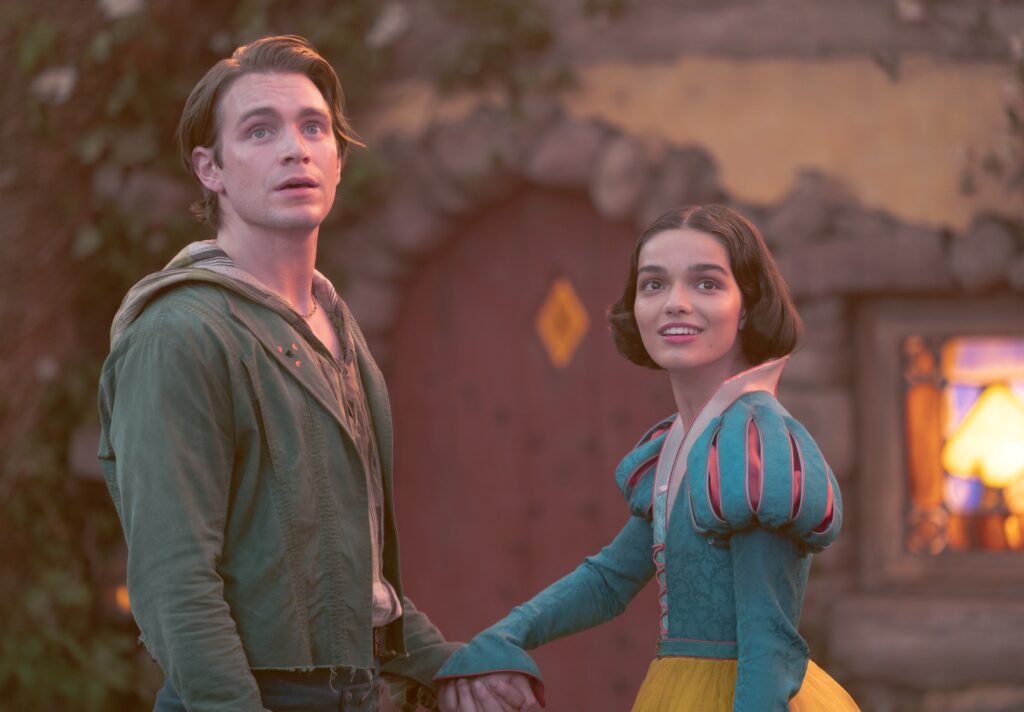 Jonathan (Andrew Burnap) looking vaguely confused, as Snow White (Rachel Zegler) holds his hand in Snow White