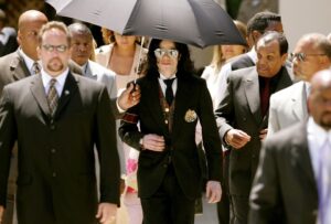 Michael Jackson and his father, Joseph Jackson, leaving a courthouse under an umbrella.