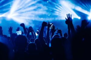 Silhouetted crowd at a concert with their hands raised.