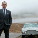 Daniel Craig as James Bond in a suit, standing in front of a classic car.