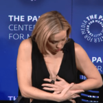 Kate Hudson adjusting her clothing at an event.