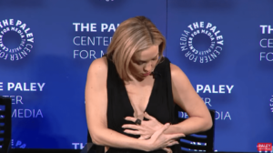 Kate Hudson adjusting her clothing at an event.