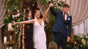 A bride and groom joyfully raise their hands at their wedding ceremony.