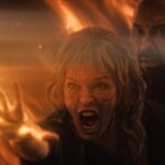 Milla Jovovich screams while using witch powers while Dave Bautista looks on in In the Lost Lands. They’re both surrounded by fire.