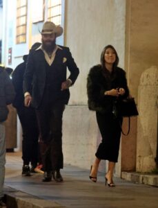 Post Malone and his rumored fiancée walking down a street at night.