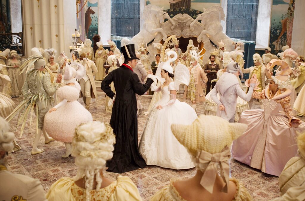 Snow White and the Prince meet in a ballroom, where everyone is dressed in an over-the-top ballgown styled like an animal. Everything is in shades of white and cream, except for the Prince, who wears a black suit and tophat with rabbit ears. Snow White’s dress is styled like a swan, complete with a swan hat. From Mirror Mirror.