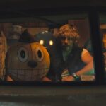 Michelle (Millie Bobbie Brown), Cosmo (a robot with a huge, grinning, round yellow head), Keats (Chris Pratt), and Mr. Peanut (who looks like Mr. Peanut) ride in a van in The Electric State