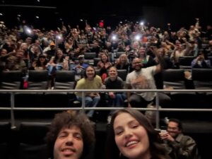 Selena Gomez and Benny Blanco at a movie screening with a large audience.