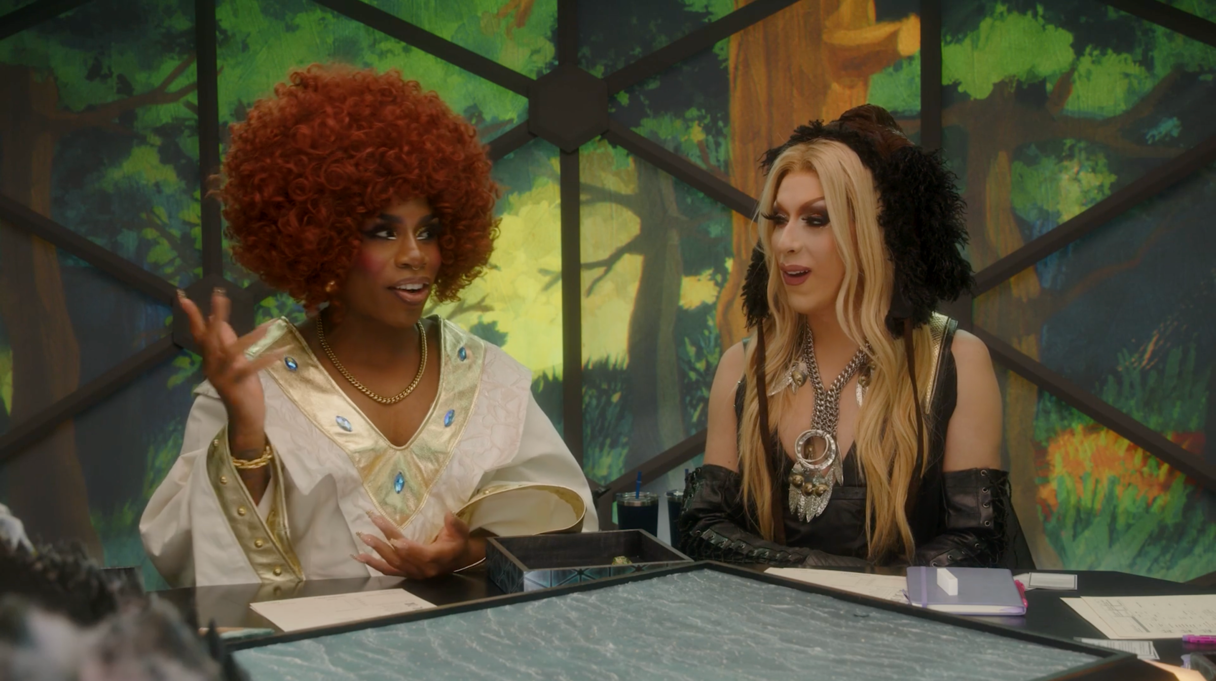 Monet X Change and Alaska Thunderfuck sitting in the Dimensional Dome in Dungeons and Drag Queens.
