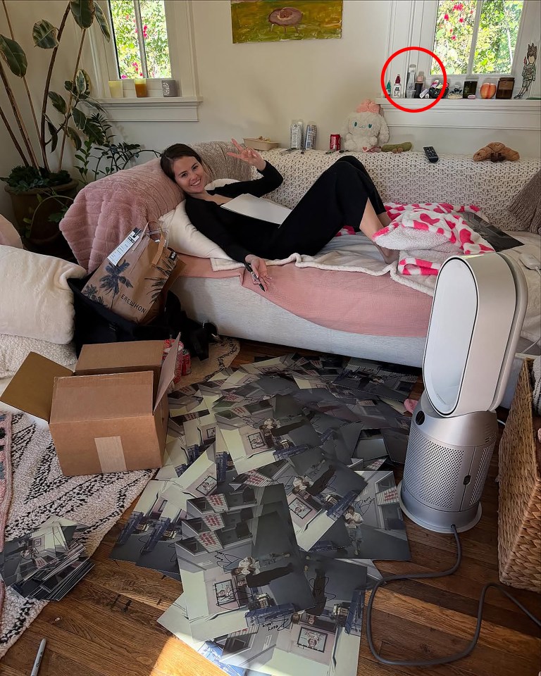 Selena Gomez relaxing on a couch surrounded by photos and packages.