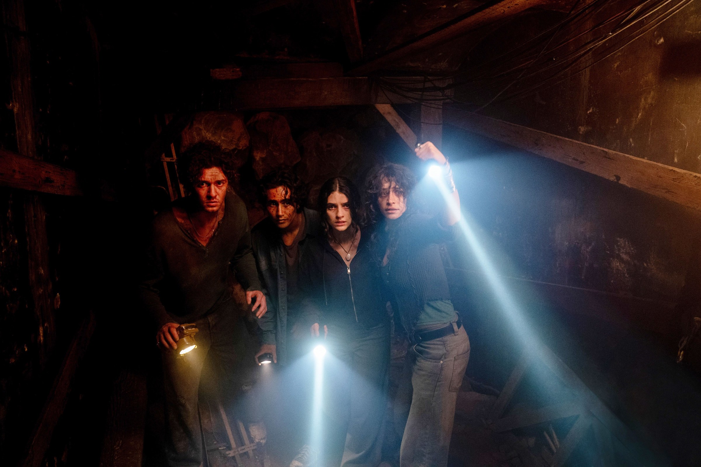A group of teenagers stand in the dark together, shining a few flashlights around a dim space, in Until Dawn