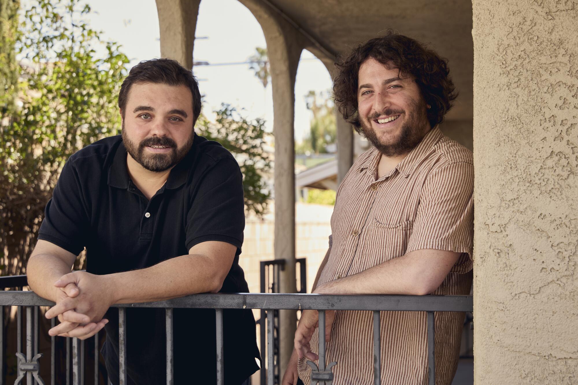 Two filmmakers smile, standing on a porch.