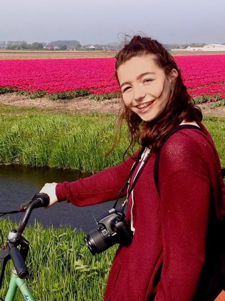 Sophie Nyweide, actress, with camera and bicycle in front of a field of tulips.