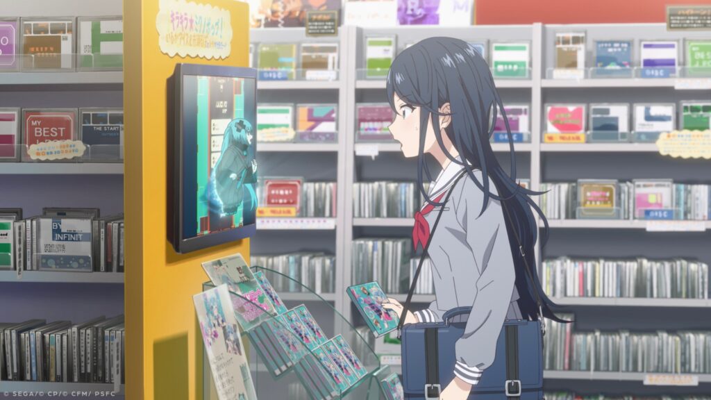A dark-haired girl in a school uniform gasps as she spots a tiny Hatsune Miku popping her head out of a wall screen in a music store. From Colorful Stage! The Movie: A Miku Who Can’t Sing