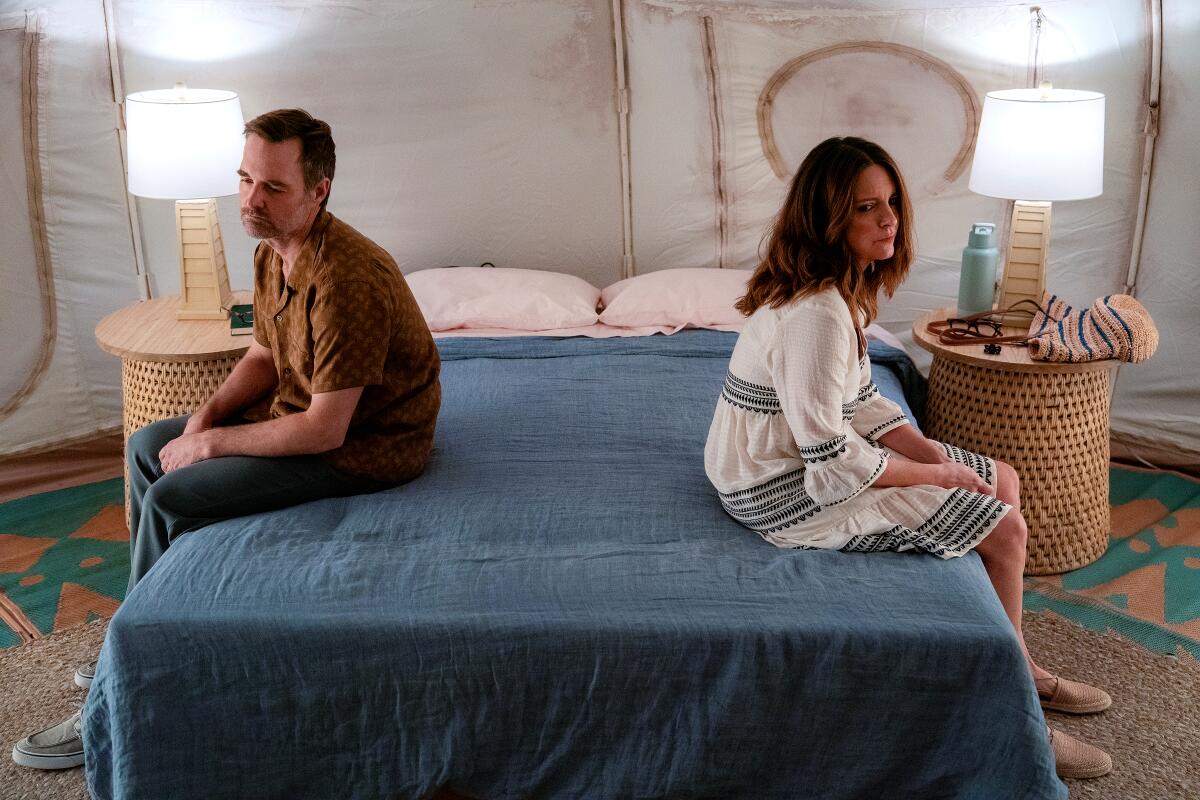 A man and a woman sit on opposite sides of a bed