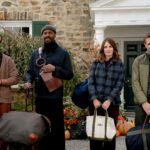 Three men and a woman stand while holding luggage