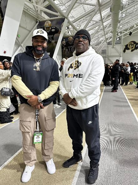 Two men in athletic wear stand together.