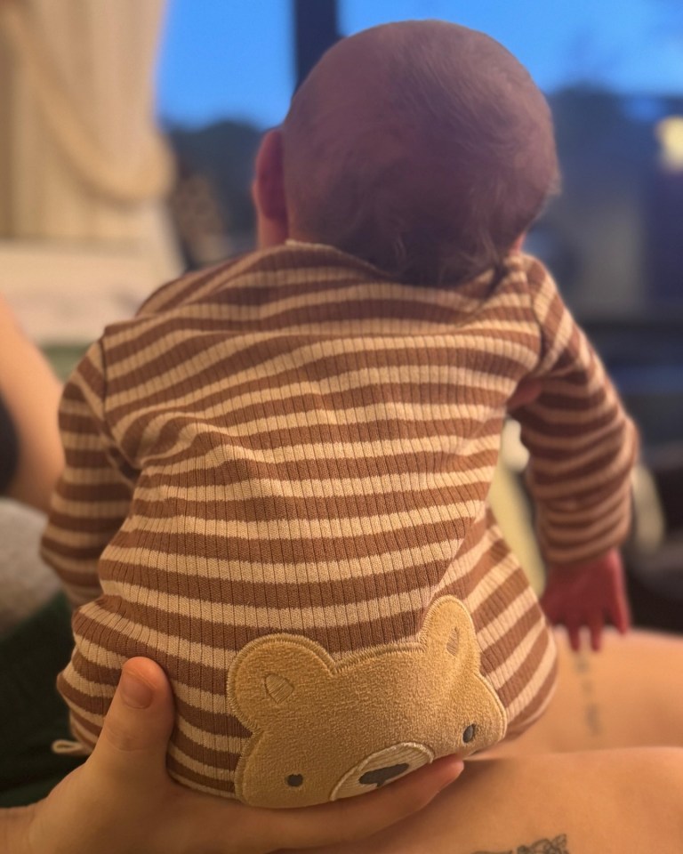 Baby in striped pajamas held by a parent.