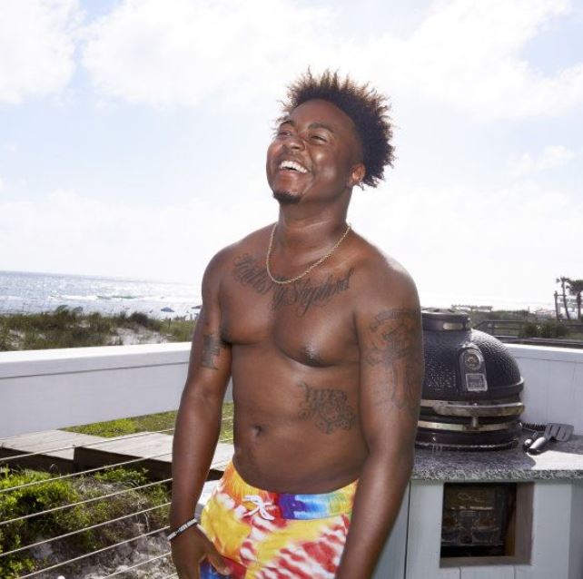 Kirk Medas, shirtless, laughing on a beach.