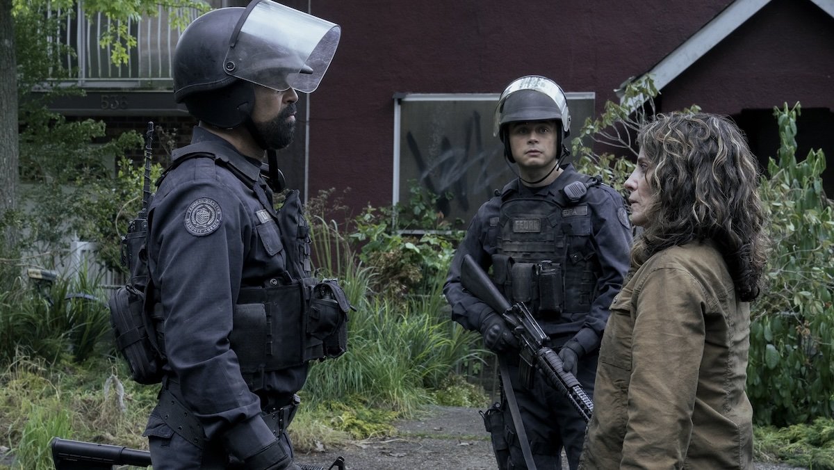 FEDRA sergeant Isaac meets with Hanrahan as a FEDRA soldier looks on in the street on The Last of Us