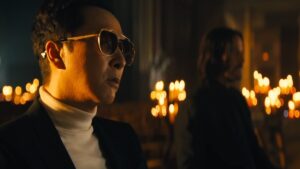 Caine in sunglasses sits in a church with John Wick opposite him in John Wick: Chapter 4
