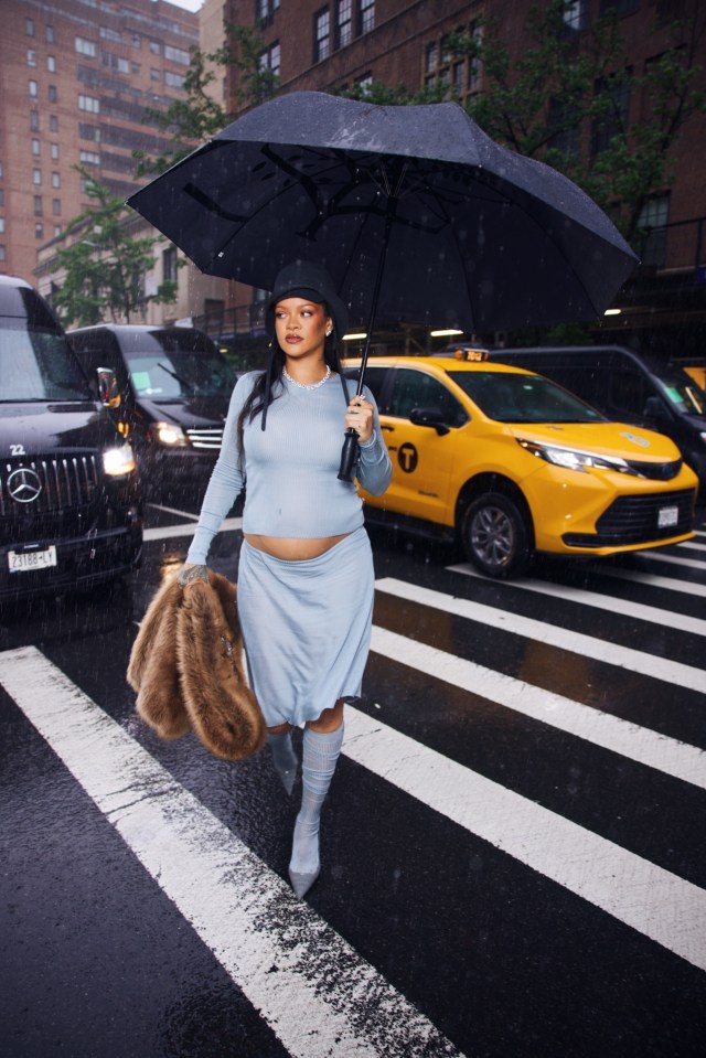 Rihanna walking in the rain, showing her baby bump.