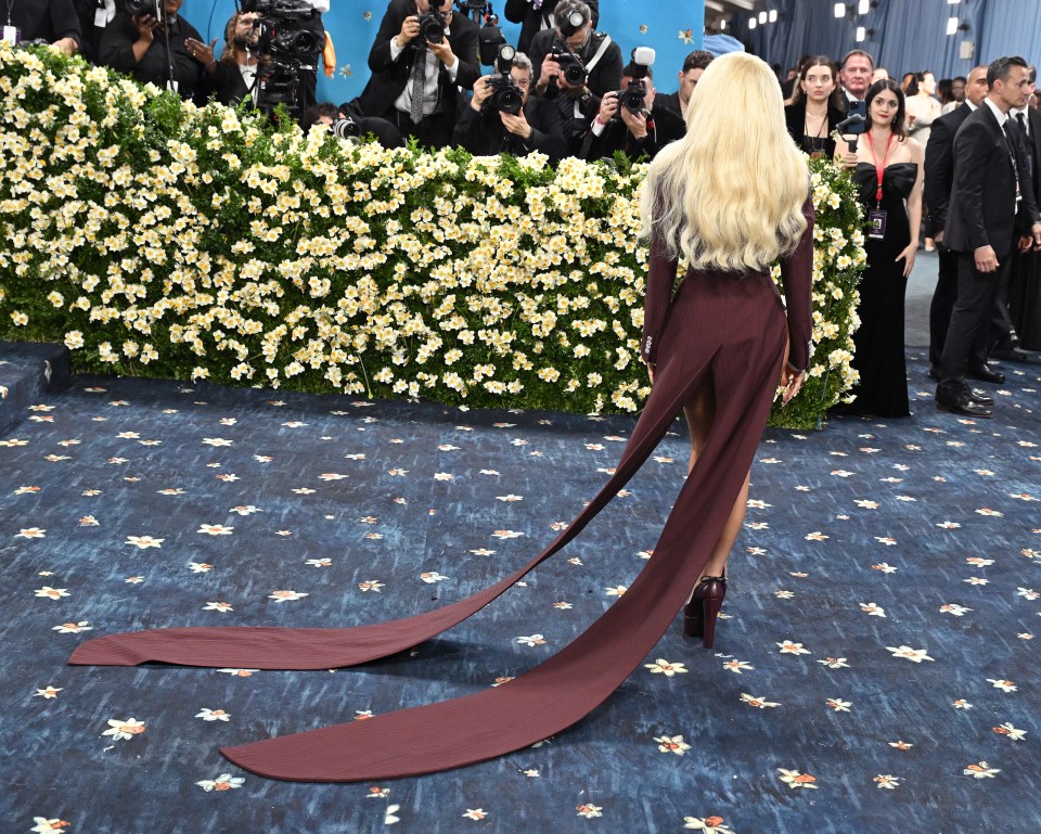 Sabrina Carpenter at the Met Gala wearing a long burgundy gown with a train.